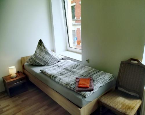 a bed in a room with a window and a chair at Ferienwohnung Karsten - nahe Chemnitz in Limbach - Oberfrohna