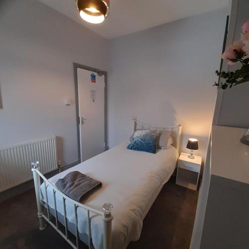 a small bedroom with a bed and a lamp at Merginn Guest House in Blackpool