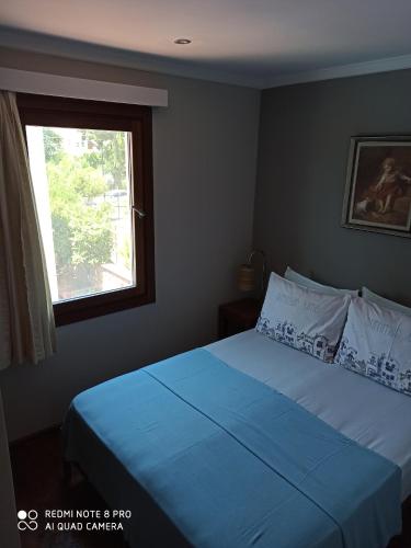a bedroom with a bed with blue sheets and a window at Stone House Hotel in Bodrum City