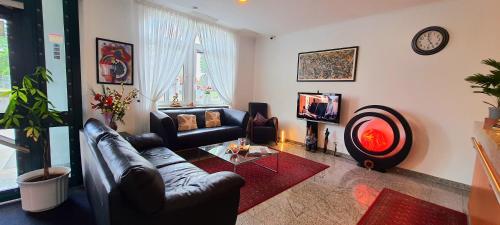 a living room with a leather couch and a tv at Hotel Deutscher Hof in Mannheim