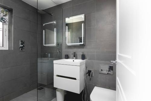 a bathroom with a white sink and a mirror at Just 20 mins from Buckingham Palace! in London
