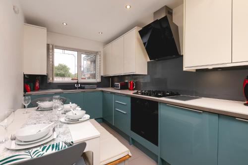 a kitchen with blue cabinets and a table with dishes at Just 20 mins from Buckingham Palace! in London