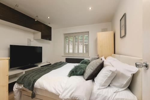 a bedroom with a large bed with a flat screen tv at Just 20 mins from Buckingham Palace! in London