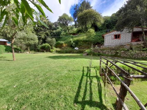 a house in the middle of a field with a fence at Acogedora cabaña cerca de La Marquesa in San Pedro Atlapulco