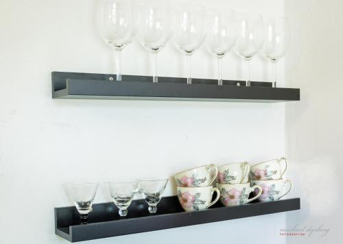 a shelf with wine glasses and cups on it at Ragnhilds Gård, Hostel Vandrerhjem in Nyord