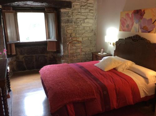 a bedroom with a bed with a red blanket and a window at Caserío Maribel in Aprícano