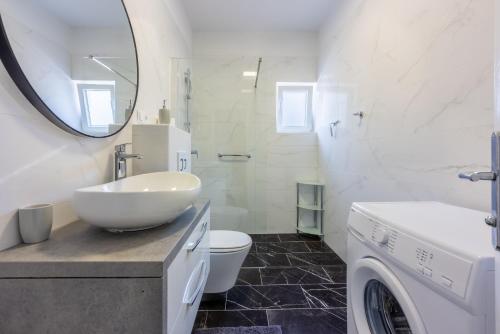 a white bathroom with a sink and a washing machine at Apartman Dora in Crikvenica