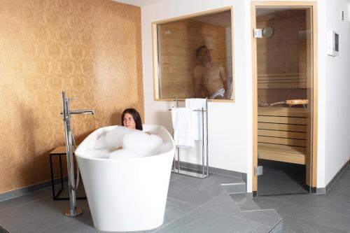 a woman sitting in a bath tub in a bathroom at Hotel Kühberg in Oberstdorf