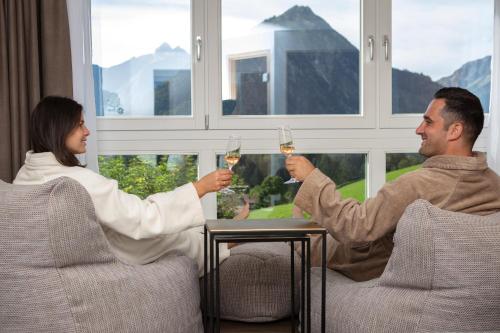 a man and woman sitting at a table drinking wine at Hotel Kühberg in Oberstdorf