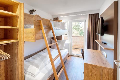 a room with two bunk beds and a desk at Hotel Kühberg in Oberstdorf
