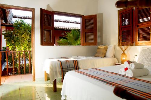 a bedroom with two beds and a balcony at Pousada Por do Sol in Jericoacoara