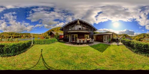 a large house on a green lawn with a fence at Chalet am Waldsee direkt am Badesee Rieden mit Seeblick für bis zu 14 Personen Traumferienhaeuser-Eifel in Rieden