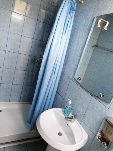 a bathroom with a sink and a blue shower curtain at Fodor Vendégház in Racu