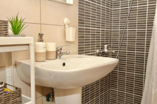 un lavandino bianco in un bagno con piastrelle nere di Lovely apartment by the sea..... a Epanomi