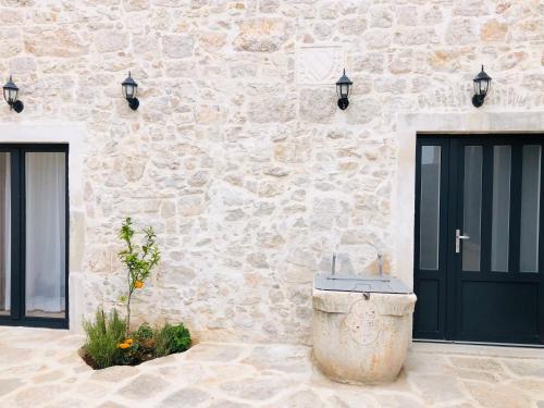 un bâtiment en pierre avec des portes noires et une fontaine dans l'établissement Villa Kata, à Preko