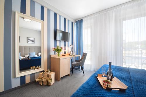 a hotel room with a bed and a desk and a mirror at Villa Nautica in Mrzeżyno