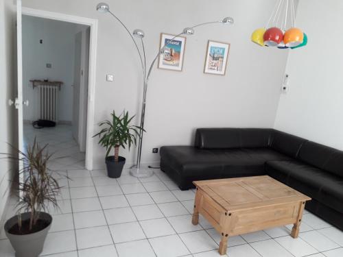 uma sala de estar com um sofá preto e uma mesa de centro em APPARTEMENT SPACIEUX em Orange
