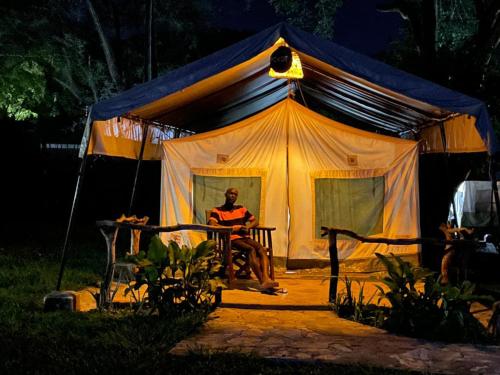 un hombre sentado dentro de una tienda por la noche en Kara-Tunga Safari Camp en Moroto