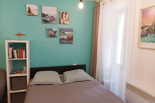 łóżko w pokoju z niebieską ścianą w obiekcie oo Le jardin oo paisible studio équipé et bien placé w mieście Quimper