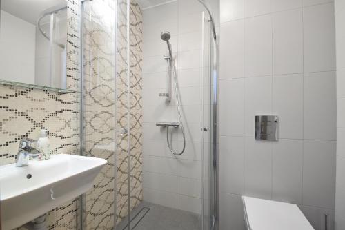 a white bathroom with a sink and a shower at Villa Nautica in Mrzeżyno