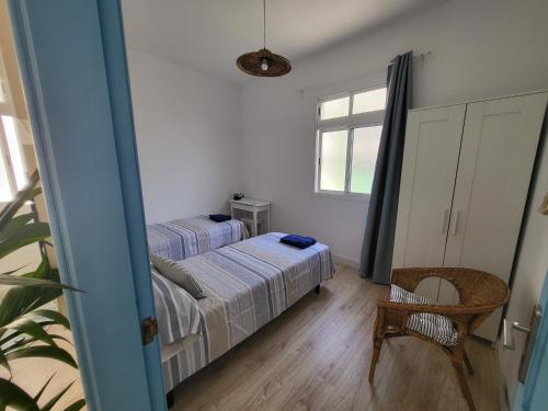 a bedroom with two beds and a chair and a window at Apartamento calandria confital para 8 con terraza y BBQ próxima playa in Las Palmas de Gran Canaria