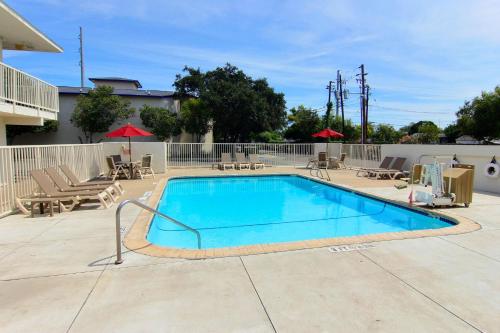 a swimming pool in a yard with chairs and umbrellas at Motel 6-Corpus Christi, TX - Northwest in Corpus Christi