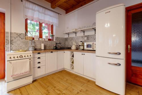 a kitchen with white cabinets and a white refrigerator at Rózsa Apartman Aggtelek in Aggtelek