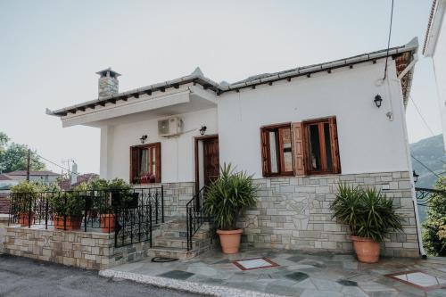 a white house with potted plants in front of it at House of Gardenia in Makrirrákhi
