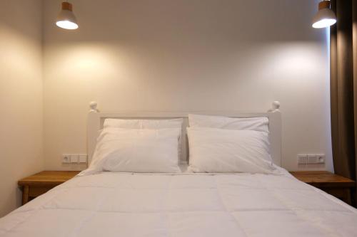a bed with white sheets and pillows in a room at Alex & Sofi Hotel in Himare