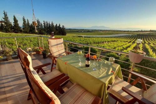a table on a balcony with a view of a vineyard at Olympus Sea View Apartment. in Nea Kalikratia