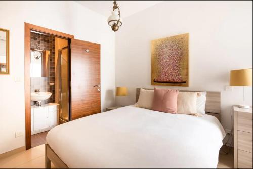 um quarto com uma cama branca e um lavatório em Luxury Seafront 2 bedroom apartment in Spinola Bay em St. Julian's