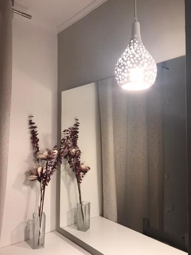 a mirror with two vases with flowers and a light at Edem in Vatera