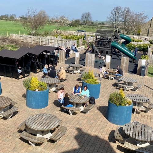 a group of people sitting on benches in a playground at The Jack and Jill Coaching Inn in Saltburn-by-the-Sea