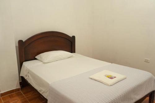 Bett mit einem Kopfteil aus Holz und einem Handtuch darauf in der Unterkunft RinaKawsay - ViveViajando HERMOSO Penthouse completamente amoblado en TENA in Tena