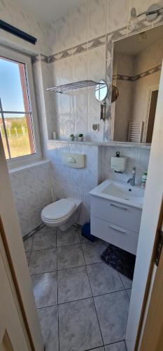 a white bathroom with a toilet and a sink at Apartament Hexagon nr 4 in Grzybowo