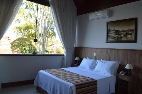 a bedroom with a bed and a large window at Pousada Terê Parque in Teresópolis
