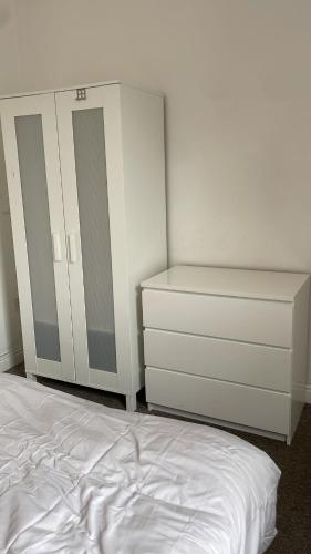 a white bedroom with a bed and a dresser at 305 High Town Road in Luton