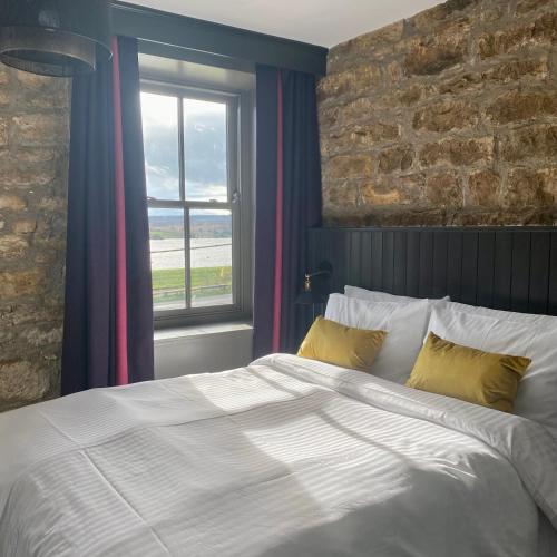 1 dormitorio con cama y pared de ladrillo en The Jack and Jill Coaching Inn en Saltburn-by-the-Sea