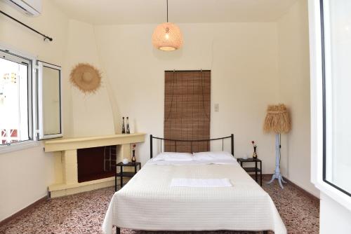 a bedroom with a bed with white sheets and a fireplace at Los Almyros in Míloi