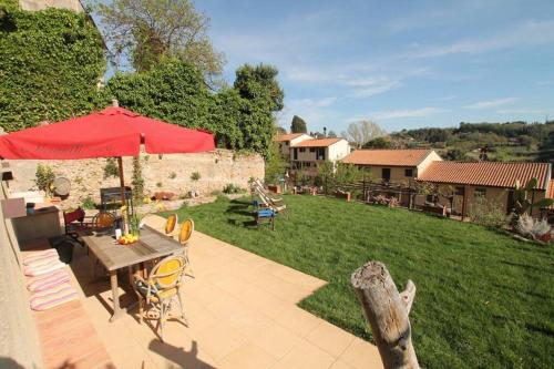 un patio con una mesa con una sombrilla roja y un patio en IL PICCINO 29, Esperienza Romantica in Borgo.... en Montescudaio