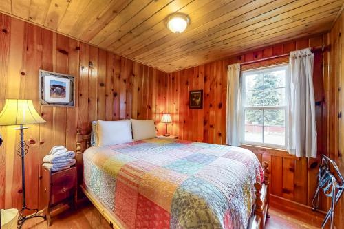 a bedroom with a bed in a room with wooden walls at River's Edge Cabin in Joseph