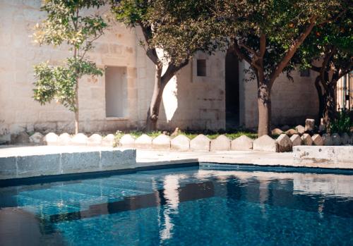 uma piscina em frente a um edifício com árvores em Tenuta Tresca Suites - Dimora Storica em San Cassiano