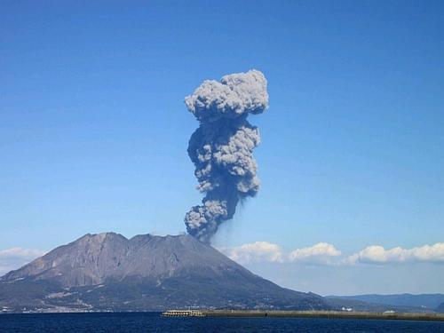a plume of smoke from a volcano in front of a mountain at Solaria Nishitetsu Hotel Kagoshima in Kagoshima