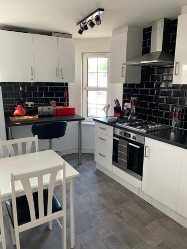 uma cozinha com armários brancos, um fogão e uma mesa em Stylish apartment in the heart of Inverness em Inverness
