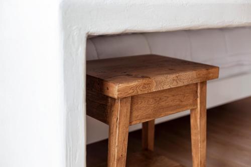 a small wooden stool sitting next to a wall at Alex & Sofi Hotel in Himare