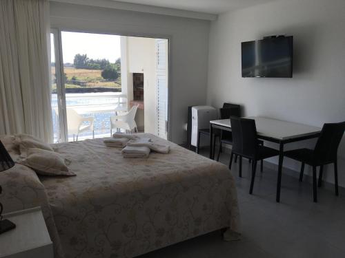 1 dormitorio con cama, mesa y ventana en Las Barrancas Apart & Spa en Necochea