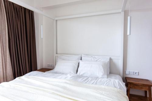 a bed with white sheets and pillows in a room at Alex & Sofi Hotel in Himare