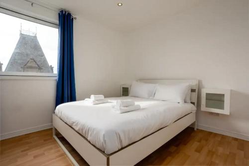 a bedroom with a large white bed with a window at Stylish 2 Bedroom Apartment near the City Centre in Edinburgh