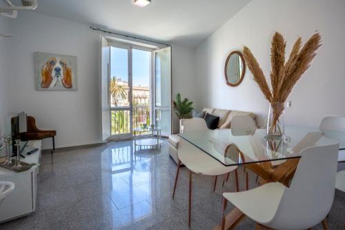 ein Wohnzimmer mit einem Glastisch und weißen Stühlen in der Unterkunft Apartamentos El Capitan Veneno by Cadiz4Rentals in Cádiz