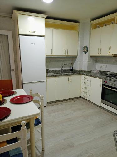 cocina con armarios blancos y nevera blanca en Habitaciones a dos pasos del congreso, en Elche